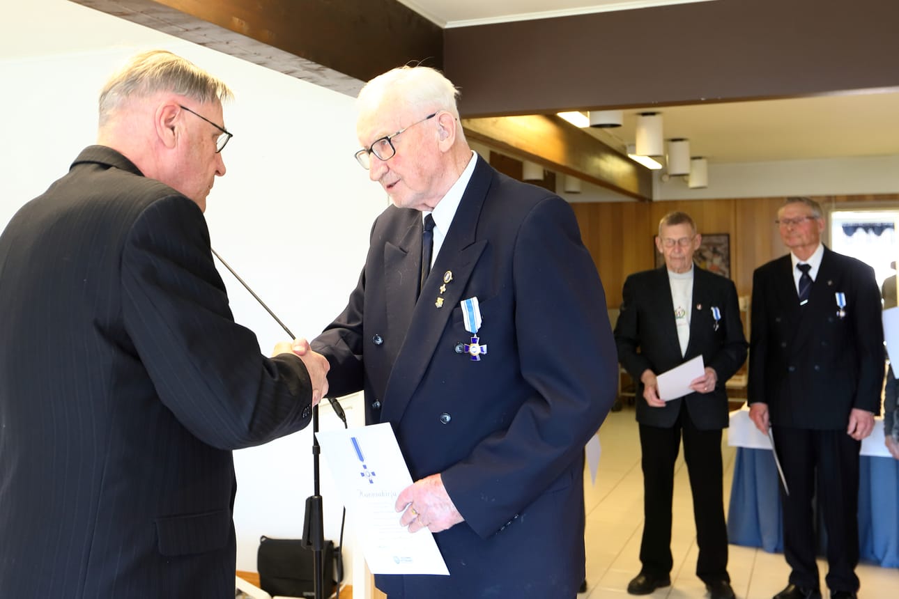 Erik Vuokila antaa Jorma Salkokarille Sotaveteraaniliiton kultaristin. Taustalla saman ristin saaneet Veikko Ranta-Eskola ja Unto Suomalainen.