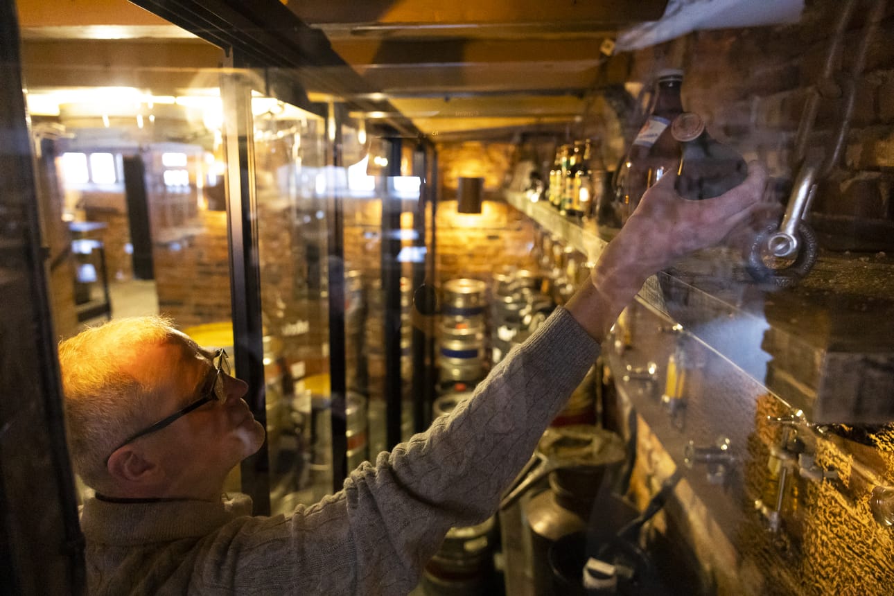 Allin Matalan ravintoloitsija Perttu Virolainen laittaa Hannu Orellin lahjoittaman 1930-luvun olutpullon esille vitriiniin.