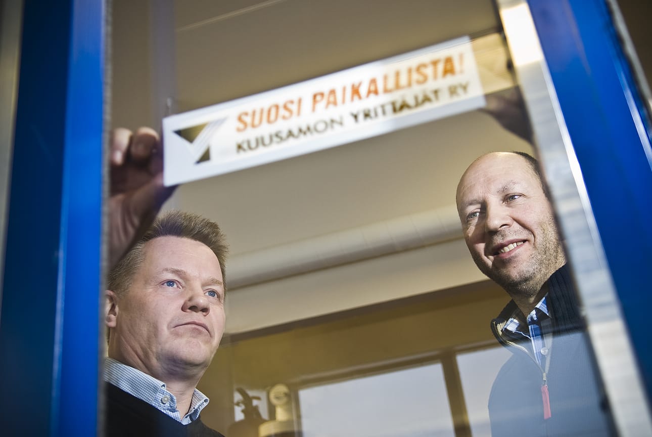 Kuusamon Yrittäjien hallituksen jäsenet Hannu Hiltula (vas.) ja Matti Pohjola esittelevät aiheesta kertovaa tarraa.