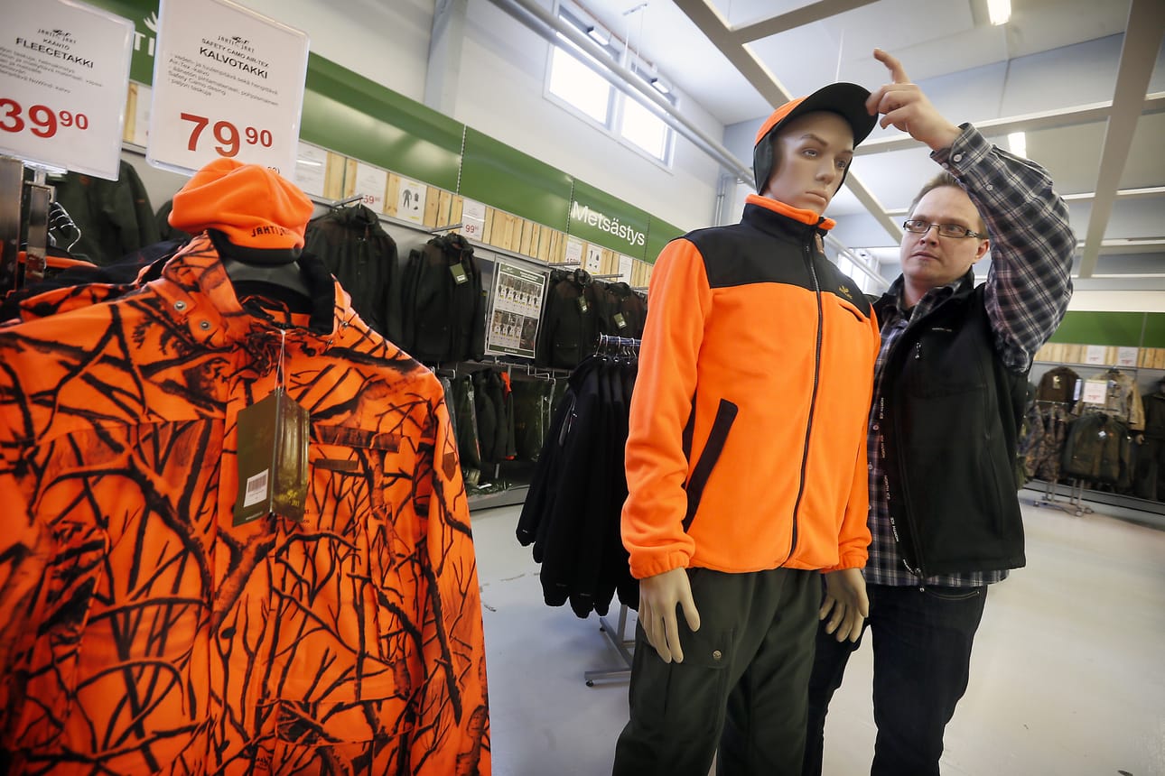 ”Oranssia tai oranssin punaista väriä on oltava vähintään kaksi kolmasosaa vaatteen ja päähineen näkyvästä pinta-alasta”, sanoo tuore asetus. Erätukun myyjä Tuomas Ronkainen asettelee mallinukelle oranssia lippalakkia.