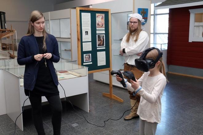 Projektityöntekijä Heidi Ala-Aho ja kirjastotoimenjohtaja Taneli Tolppanen neuvoivat tarvittaessa kädestä pitäen, kuinka virtuaalilasit päässä pelataan. Aino Peltoluhta oli yksi ennakkoluulottomista kokeilijoista. KUVAT: ANU NAHKALA