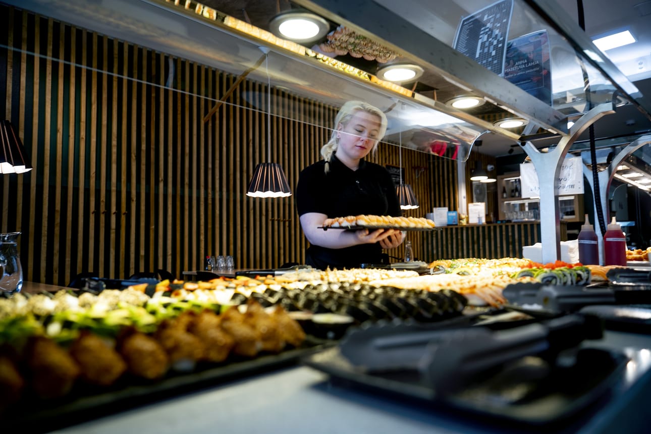 Tarjoilija Satu Nevala viimeisteli ravintola Jukun sushipöytää keskiviikkona. Korona-aika ja tämän hetkinen maailmantilanne näkyvät lounaspaikkojen hinnastoissa.
