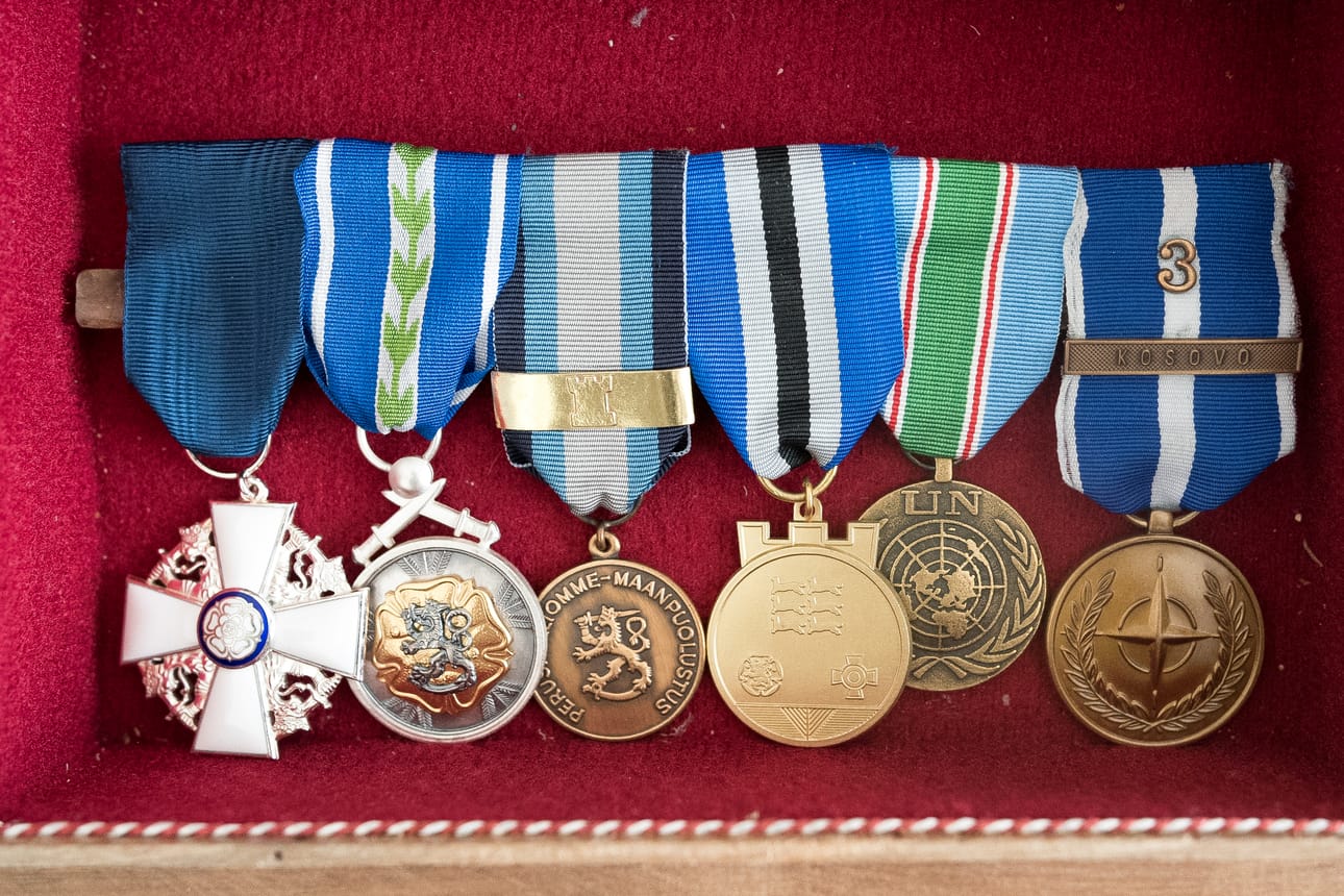 Mitaleita, joista vasemmalla Suomen Valkoisen Ruusun Ritarimerkki ja oikealola Nato-mitali.