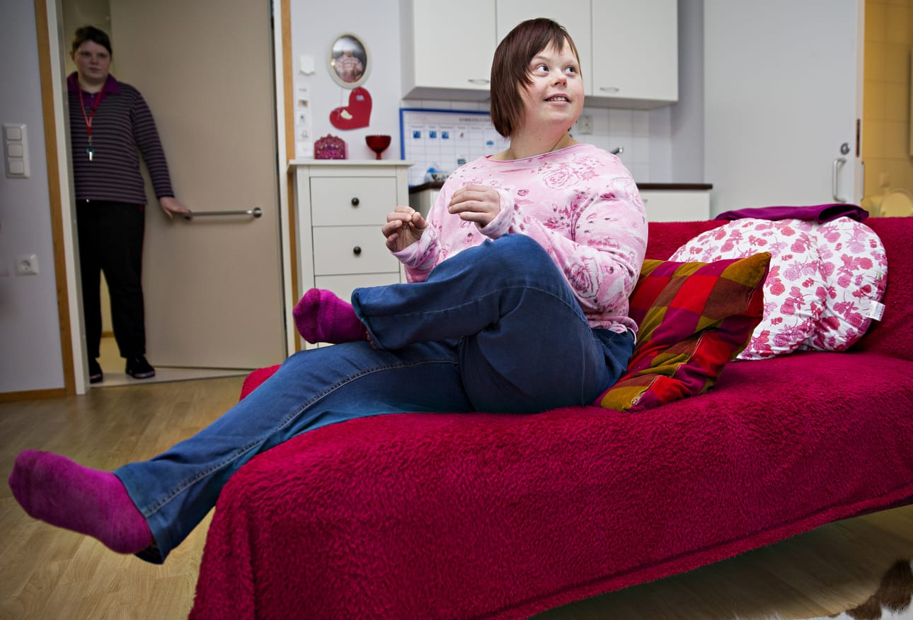 Saara Suikki tykkää viettää aikaa huoneessaan Kangasrouskun palvelukodissa. Taka-alalla näkyvä opiskelija Marja Ansamaa kertoo, että maksujen isot korotukset ovat puhuttaneet paljon.