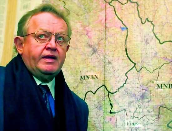 Martti Ahtisaari poseeraa Kosovon kartan edessä.