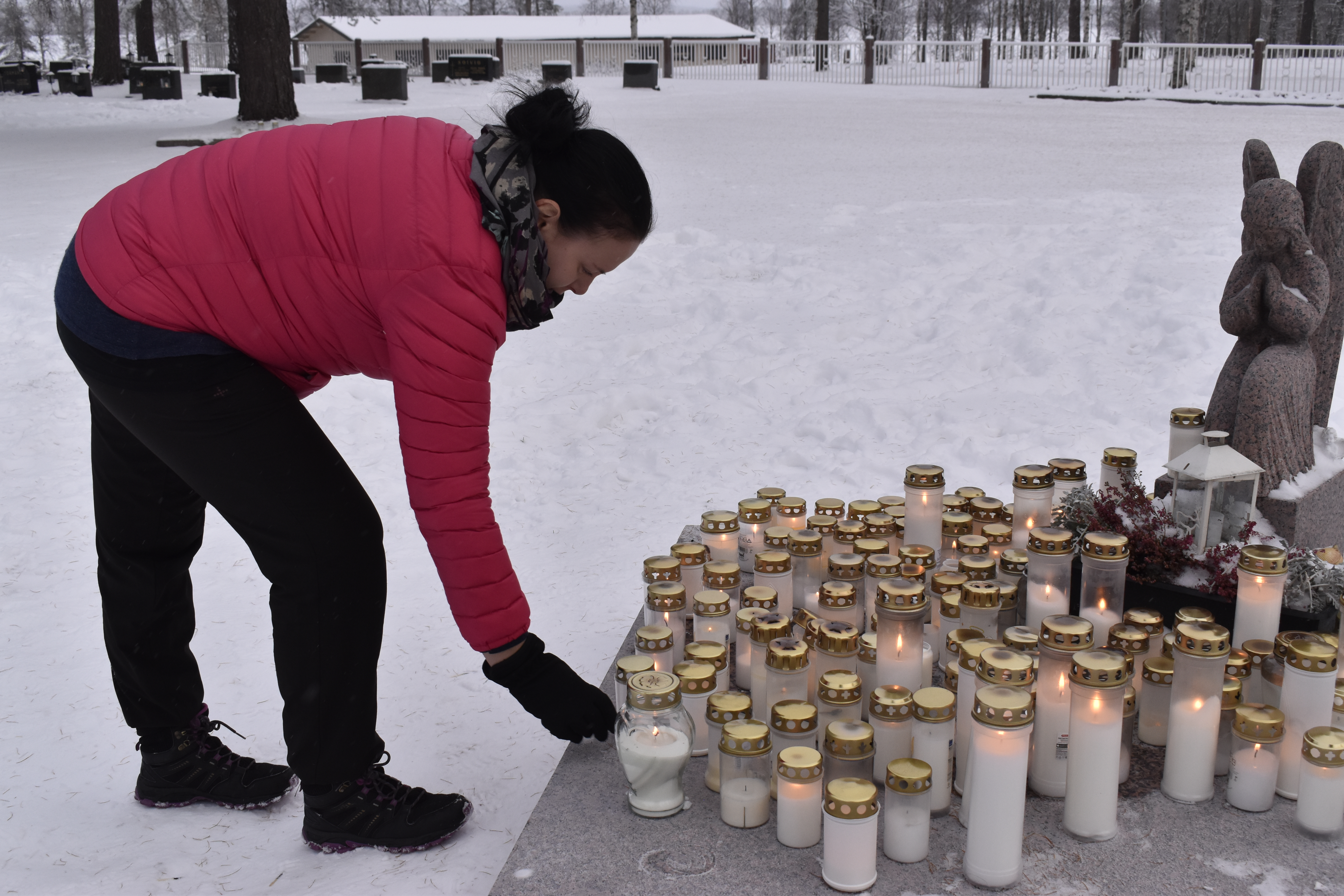 Anne Lonnakko sytyttää kynttilän mummin ja ukin muistolle Pyhän Ristin kirkkomaalla.