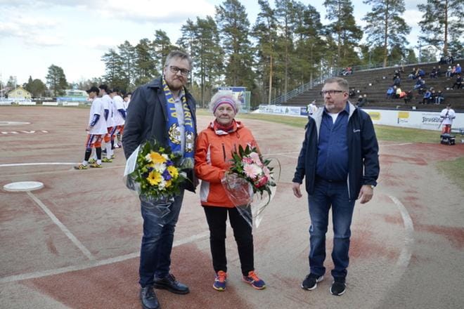 80-vuotias talkoolainen Miina Mariapori sai Ankkureilta onnittelukukat ja samalla kiitosta tekemästään talkootyöstä seuran puheenjohtajalta Antti Joensuulta (vas.) ja markkinointipäälliköltä Jouko Salmenautiolta. Kuva: Markku Turpela