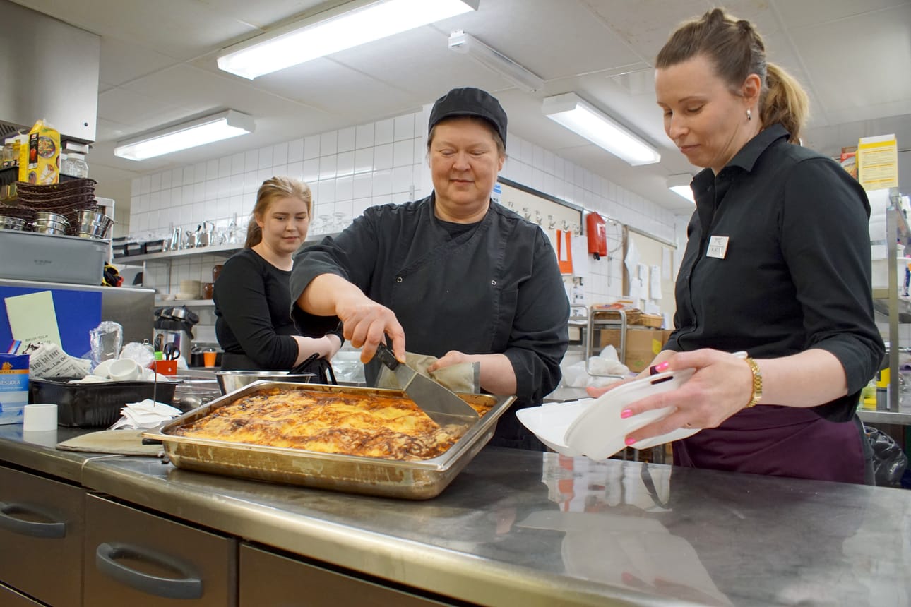 Tarjoilija Iina Valkama (vasemmalla) ja myyntikoordinaattori Kati Alatalo varmistivat kun kokki Pia-Maarit Valkama pakkasi asiakkaan tilaamaa ylijäämäannosta Pikku-Syötteen keittiössä.