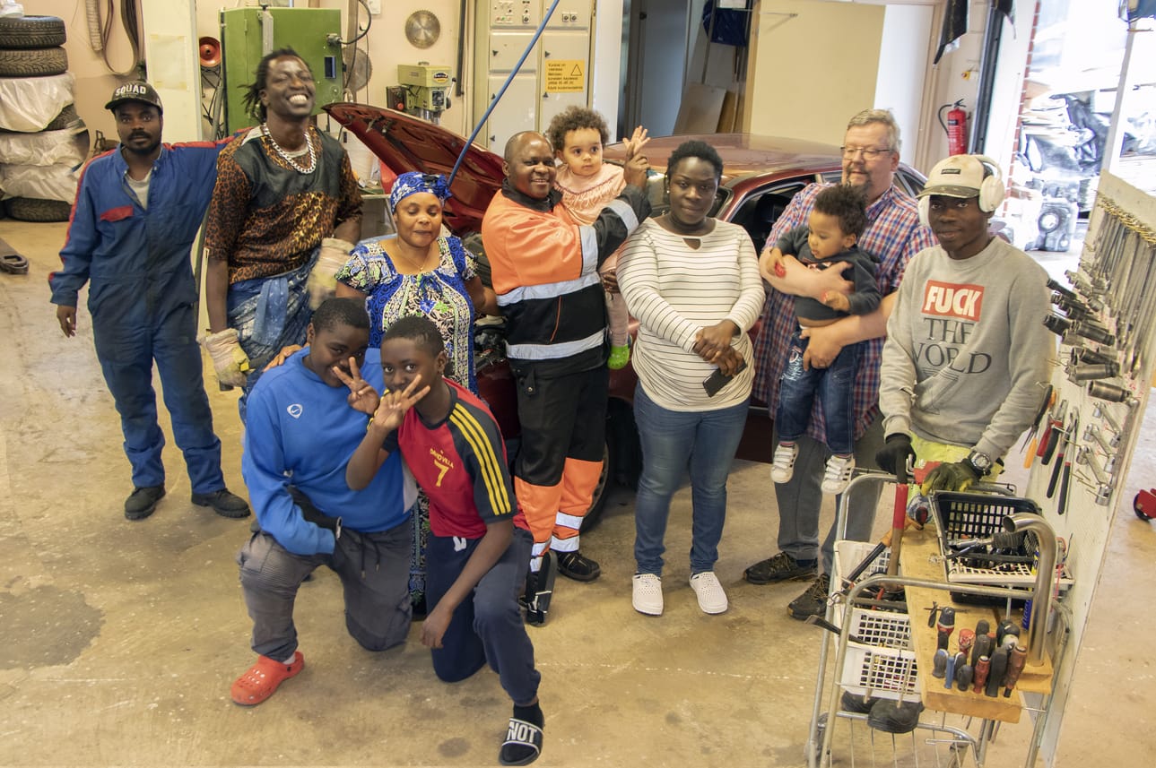 Juha (toinen oik. sylissä poika Mooses) ja Melissa Kokkisen omistaman Ponnarin tiloissa toimiva Finn Reuse Oy vie autoja ja käyttötavaraa Afrikkaan. Maanantaina tiloissa pakattiin vilskeellä tavaraa merikuljetusta varten. Vas. Damas Sibomana, Lamin Jaiteh, Adele ja Agustinus Sibomana sylissään pojantytär Anastasea. Oikealla Mawuli Kuse ja edessä apupojiksi saapuneet Jean Perre ja Nathan.