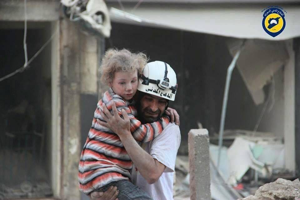Syria Civil Defence -järjestön vapaaehtoinen kantoi sylissään lasta Aleppossa. Kuvanottohetki ei ole tiedossa.