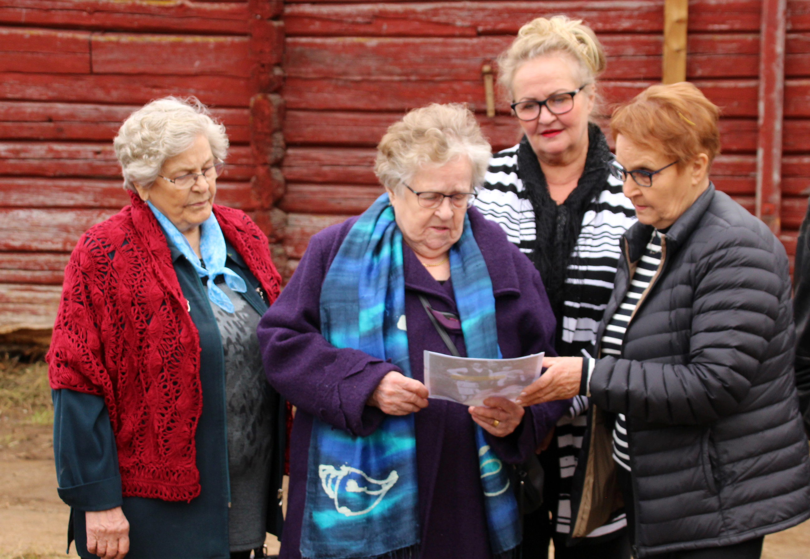 Elsa Pohjola, Marketta Sippola, Raili Sippola ja Hilkka Patosalmi tutkivat kuvaa, joka on otettu Hilkan perheestä Ojalan talon pihassa.
