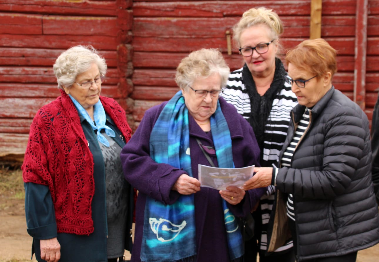 Elsa Pohjola, Marketta Sippola, Raili Sippola ja Hilkka Patosalmi tutkivat kuvaa, joka on otettu Hilkan perheestä Ojalan talon pihassa.