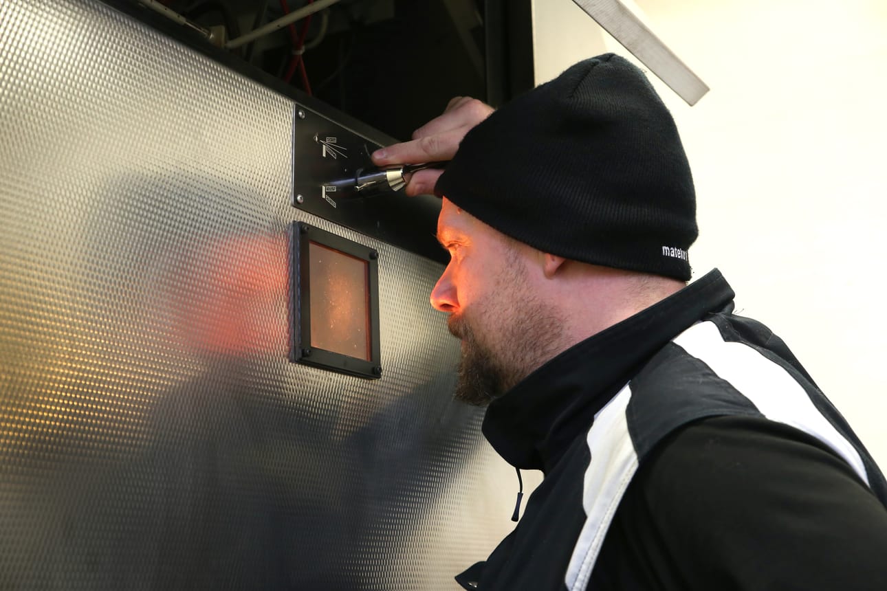 Jari Väänänen tarkkailee polttoprosessia sekä tietokoneen näytöltä että krematorion uunin pienestä ikkunasta.