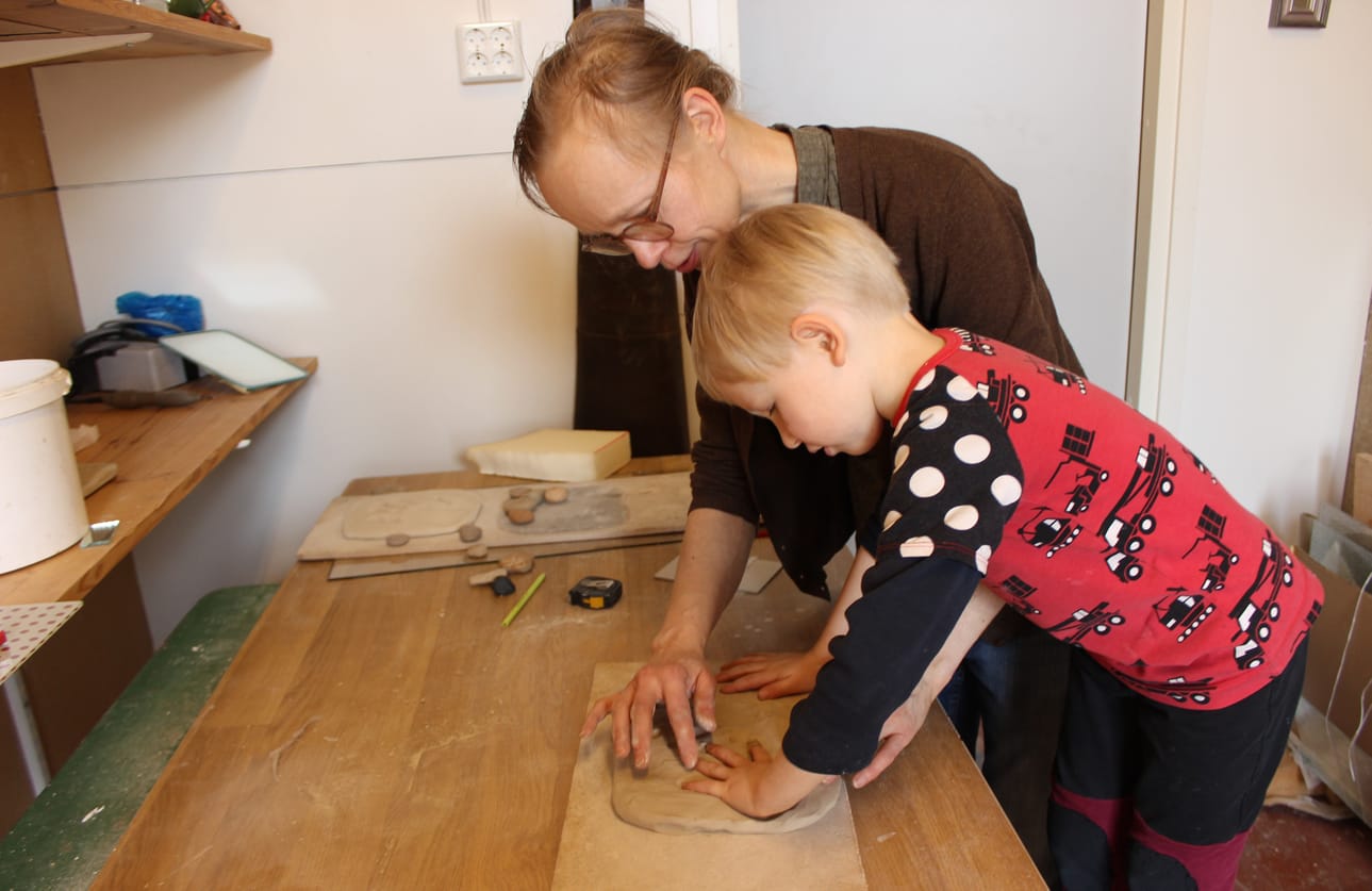 Niina Riska valmistaa poikansa Timotin kanssa Kaskisiin valmistuvan tulevaisuusteoksen ensimmäistä savilaattaa.