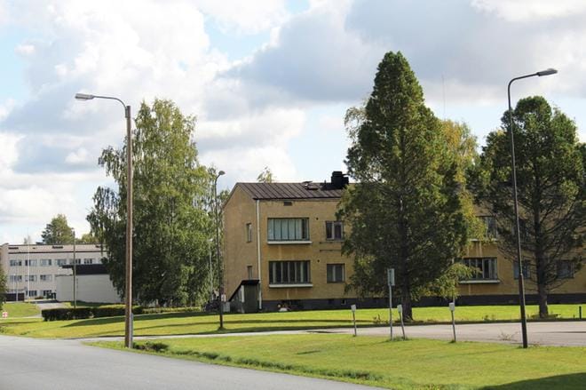 Keltainen kerrostalo on yksi neljästä talosta, jotka ovat Kauhavan vastaanottokeskuksen perheasukkaiden käytössä entisen lentosotakoulun alueella. Takana näkyvät vanhat kasarmit ovat tyhjillään. KUVA: MIA KÄRKKÄINEN