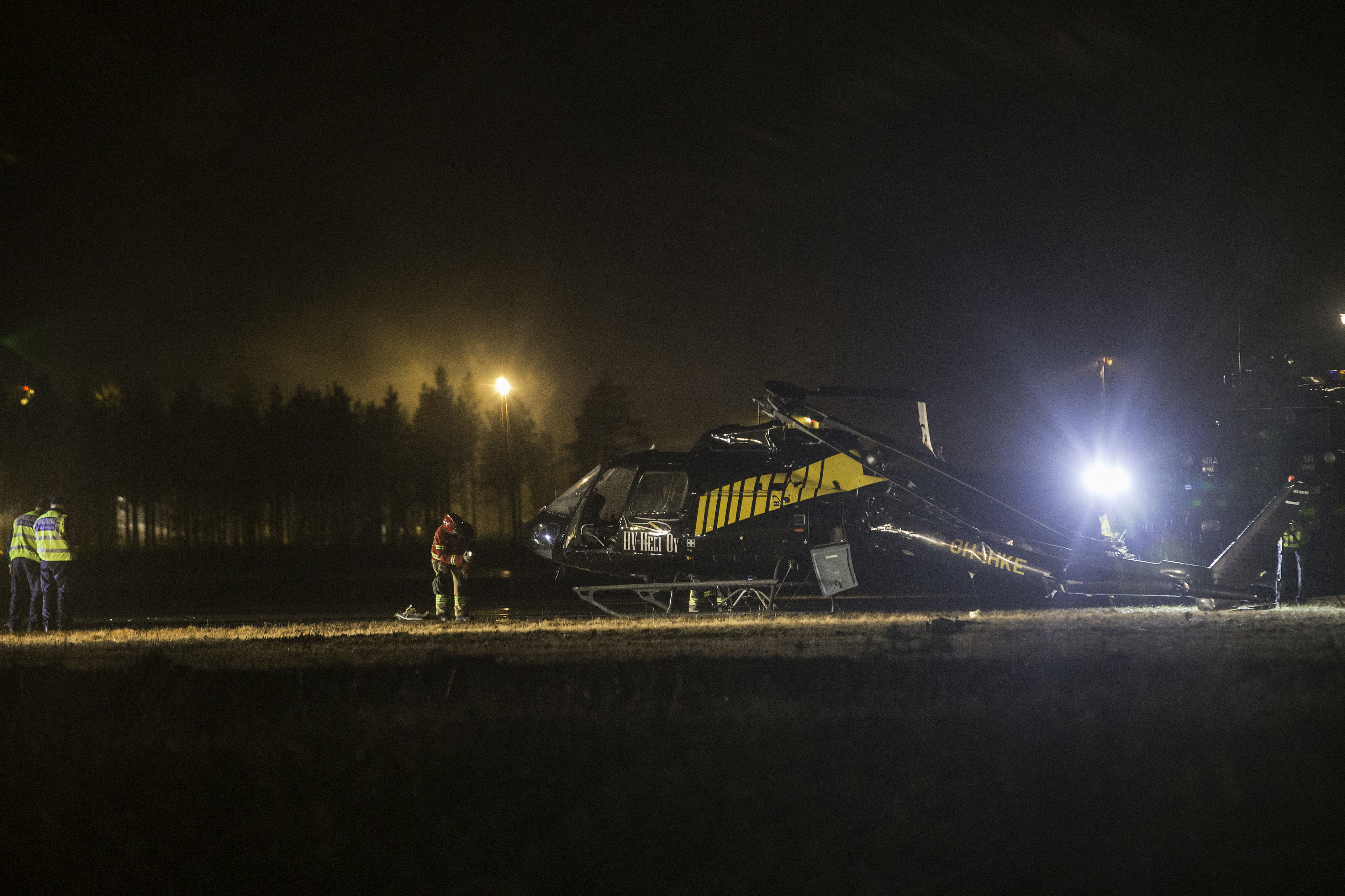 Helikopteri seisoo kentällä epätasapainossa, ja sen peräroottorin puomi on painunut alas maata kohti.