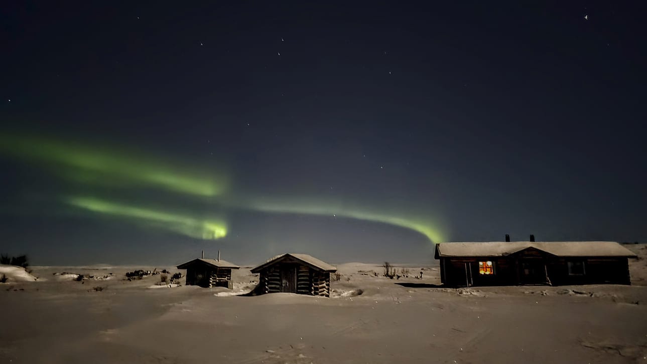 Pöyrisjärven autiotupa revontulien ja kuun loisteessa.