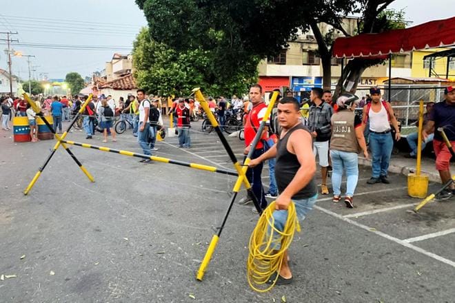 Venezuelalaiset siirsivät turvallisuusjoukkojen asettamia esteitä avun tieltä Urenan rajakaupungissa Kolumbian vastaisella rajalla lauantaina. Kuva: Hector Pereira
