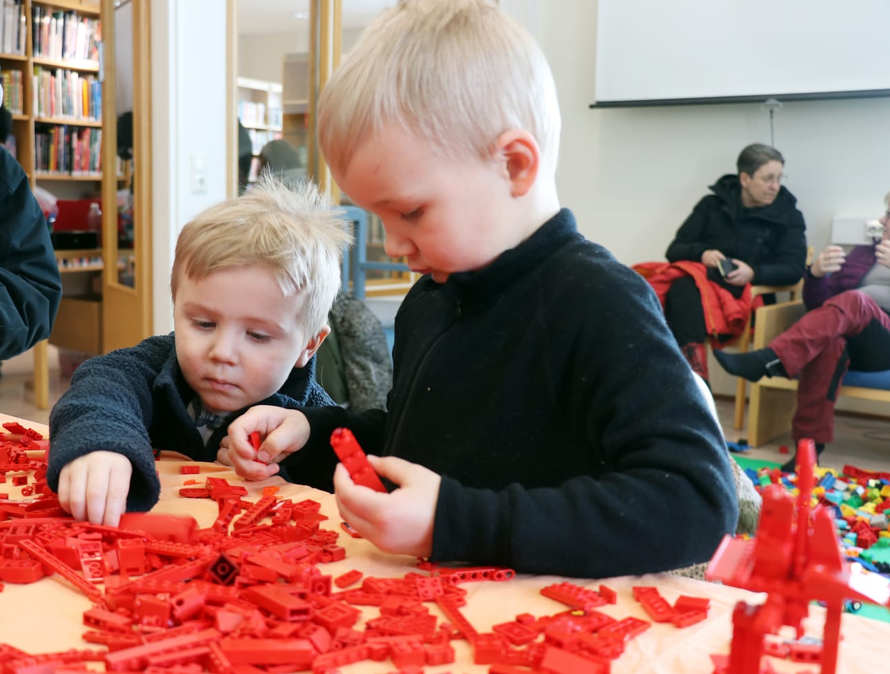 Lenni ja Veeti Hauta-aho etsivät keskittyneesti oikeanlaisia palikoita Alajärven kirjaston Lego-tapahtumassa.