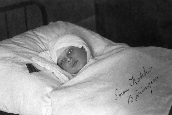 Onni Kokko (1904–1918) makaa sairaalassa ennen kuolemaansa keväällä 1918. Hänen vieressään on Mannerheimin myöntämä vapaudenristi. Kokko on edelleen Suomen historian nuorin vapaudenristin saanut sotilas. KUVA: Riitta Svanbäckin Arkisto