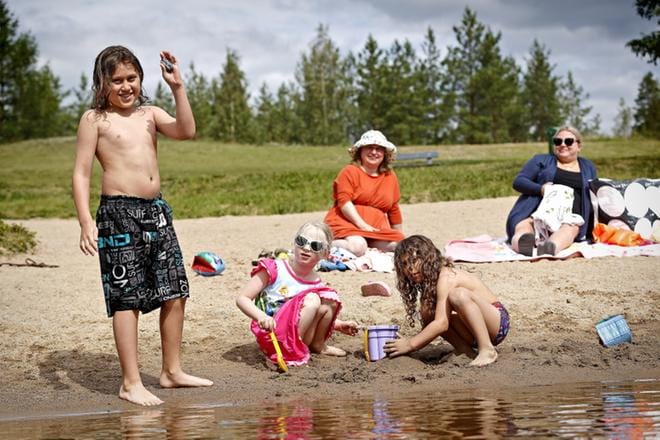 Ayman Ayida (vas.), Wilma Udelius ja Nasser Ayida eivät välitä, vaikka Tanelinrannalla vesi on viileää. Sanna Paloluodon ja Heidi Udeliuksen on helppo istuskella rannalla, kun lapset viihtyvät. KUVAT: KARI LÖFJELM