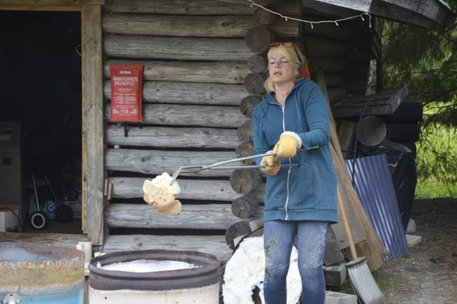 Turvallisuus ennen kaikkea. Satu Ojala tarttuu pihdeillä raku-uunissa tulikuumiksi paistuneisiin esineisiin. Uunista esineiden matka jatkuu savustuspönttöön.