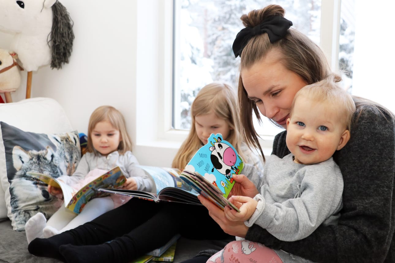 Minka ja Kiana Salmela ovat ahkeria kirjaston käyttäjiä. Myös äiti Susanne Salmelan sylissä istuva kymmenkuinen Kalla tykkää katsella kuvakirjoja.