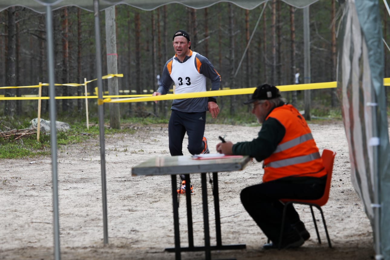 Seppo Pietilä (etualalla) kirjaa ajan, kun Kainuun piirin Seppo Seppänen (33) saapuu maaliin.