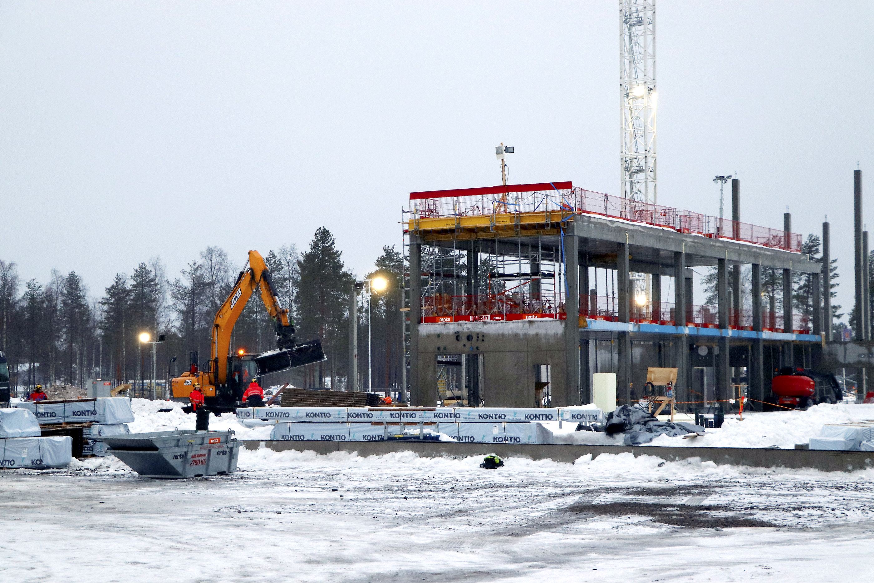 Kontion hirret saapuivat Hyvän olon keskuksen työmaalle tiistaiaamuna (kuva vasemmalla). Rakennukset salvetaan betonisen rungon päälle osasto kerrallaan (kuva oikealla). Lopuksi päälle nostetaan lohkoina maassa rakennettu katto.