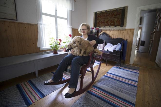 Kesälomaansa isänsä äidin kotitalossa viettävä suurlähettiläs Helena Tuuri saa keinutuoliinsa välittömästi seuraa, kun Doris ja Artturi hyppäävät koiraihmiseksi tunnustautuvan emäntänsä syliin vanhassa tupamiljöössä. KUVAT: MARIA MÄKI
