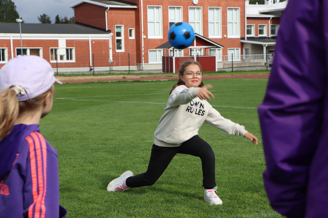 Sofia heittää palloa tarkoituksenaan osua ympyrän sisällä oleviin leikkijöihin.