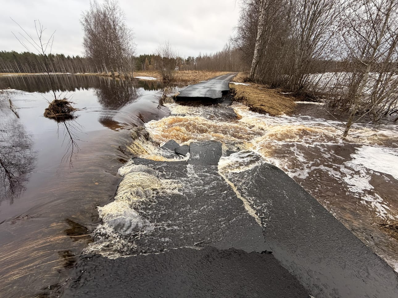 Asfalttipintainen tie murtui virtaavan veden alla.