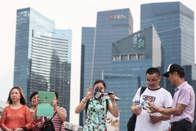 Singapore on kapitalismin ja hyvinvoinnin ilmentymä, joka varmasti tekee Pohjois-Korean Kim Jong-uniin vaikutuksen. Turistit ottavat kuvia kaupunkivaltion finanssikeskuksen pilvenpiirtäjien edustalla. KUVA: EPA/WALLACE WOON