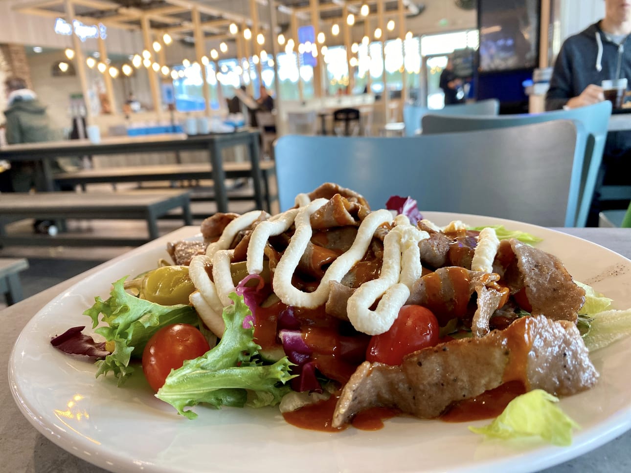 Kebabc!-annos salaatilla tuodaan pöytään. Sisustuksessa on käytetty puuta ja ravintolasalin valaistukseen on panostettu.