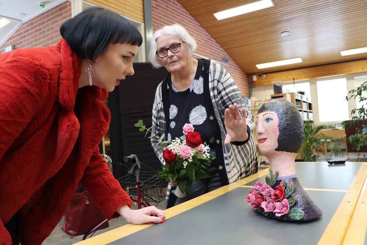 Susanna Erkinheimo katseli tarkasti näköispatsastaan Jurvan kirjastolla, jossa Eila Mäkinen luovutti sen hänelle kukkien kera.