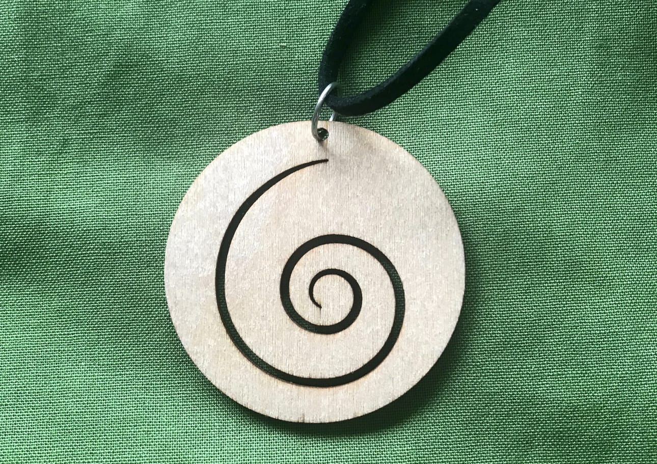 Naislaulajien kaulakorussa komeilee kuoron logo, korvan kuulosimpukka.