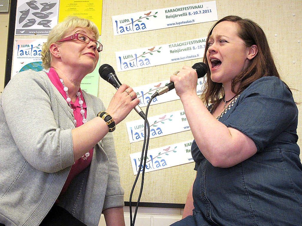 Projektisihteeri Tiina Kesänen (vas.) ja tapahtumapäällikkö Marita Pasanen virittelevät tässä tunnelmia Lupa laulaa -karaoketapahtumaan, joka järjestetään heinäkuussa Reisjärvellä.