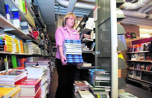 Kädet venyvät. Libristi Anne Virkkula kiikuttaa kirjoja Suomalaisen kirjakaupan varastosta kohti myyntipöytiä.