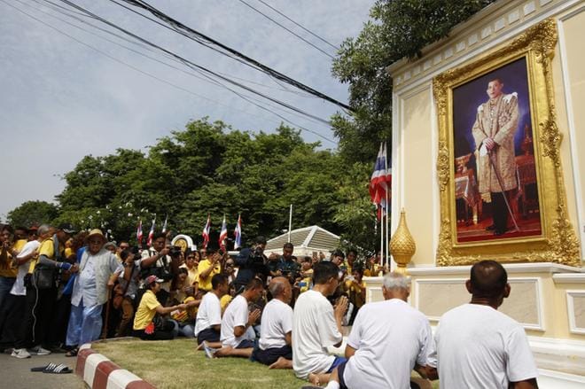 Kuningas Maha Vajiralongkorn (taulussa) on viettänyt virallisia kruunajaisiaan muun muassa armahtamalla tuhansia vankeja. Vapautetut vangit rukoilivat kuninkaan kuvan edessä Bangkokissa perjantaina. KUVA: NARONG SANGNAK/EPA
