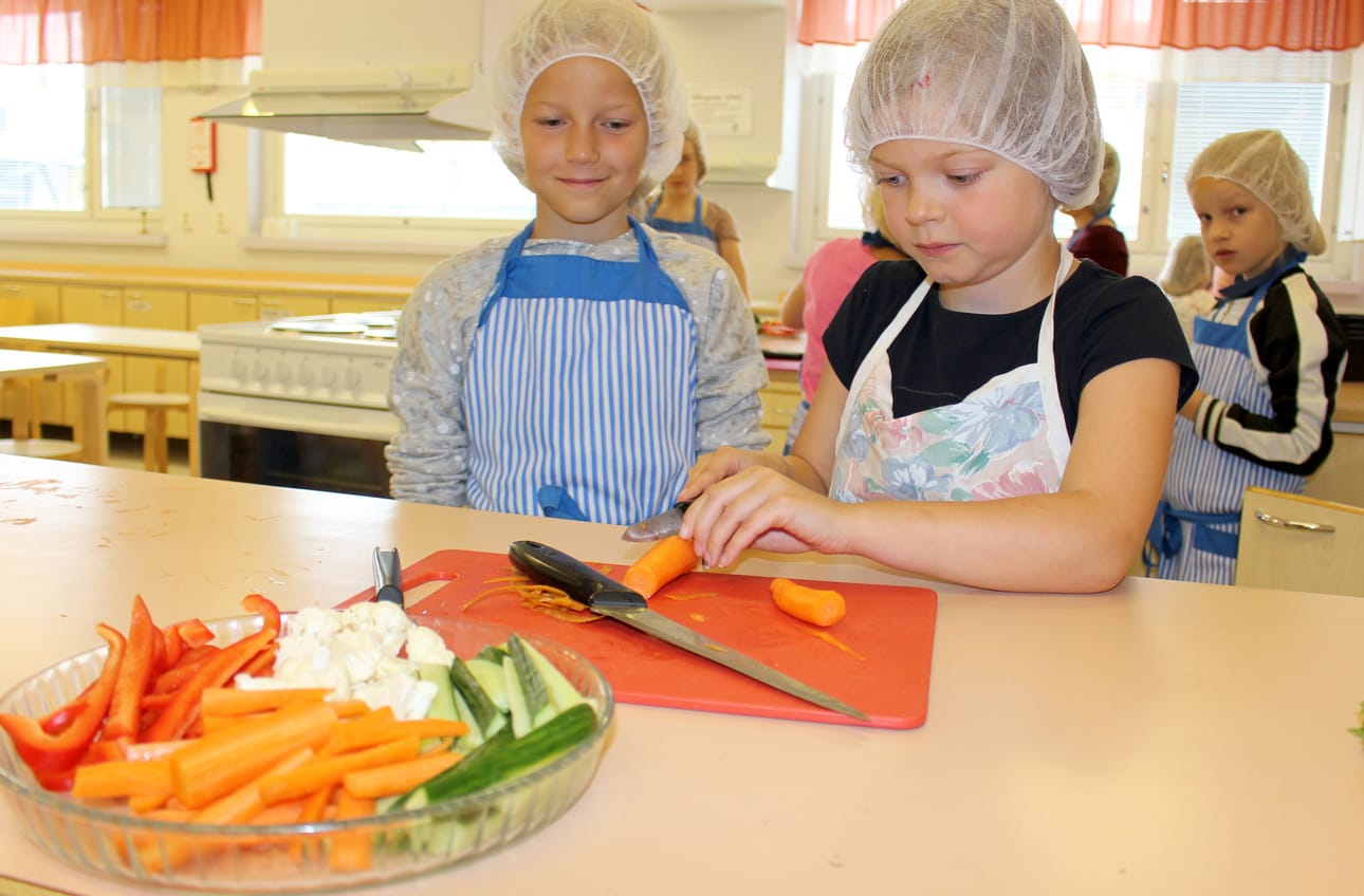Kokkikerhossa valmistettiin tiistaina dippi kasviksia. Sara Huhtala vei jo porkkanankuoret roskiin ja Emma Leinonen pilkkoo viimeiset porkkanat.