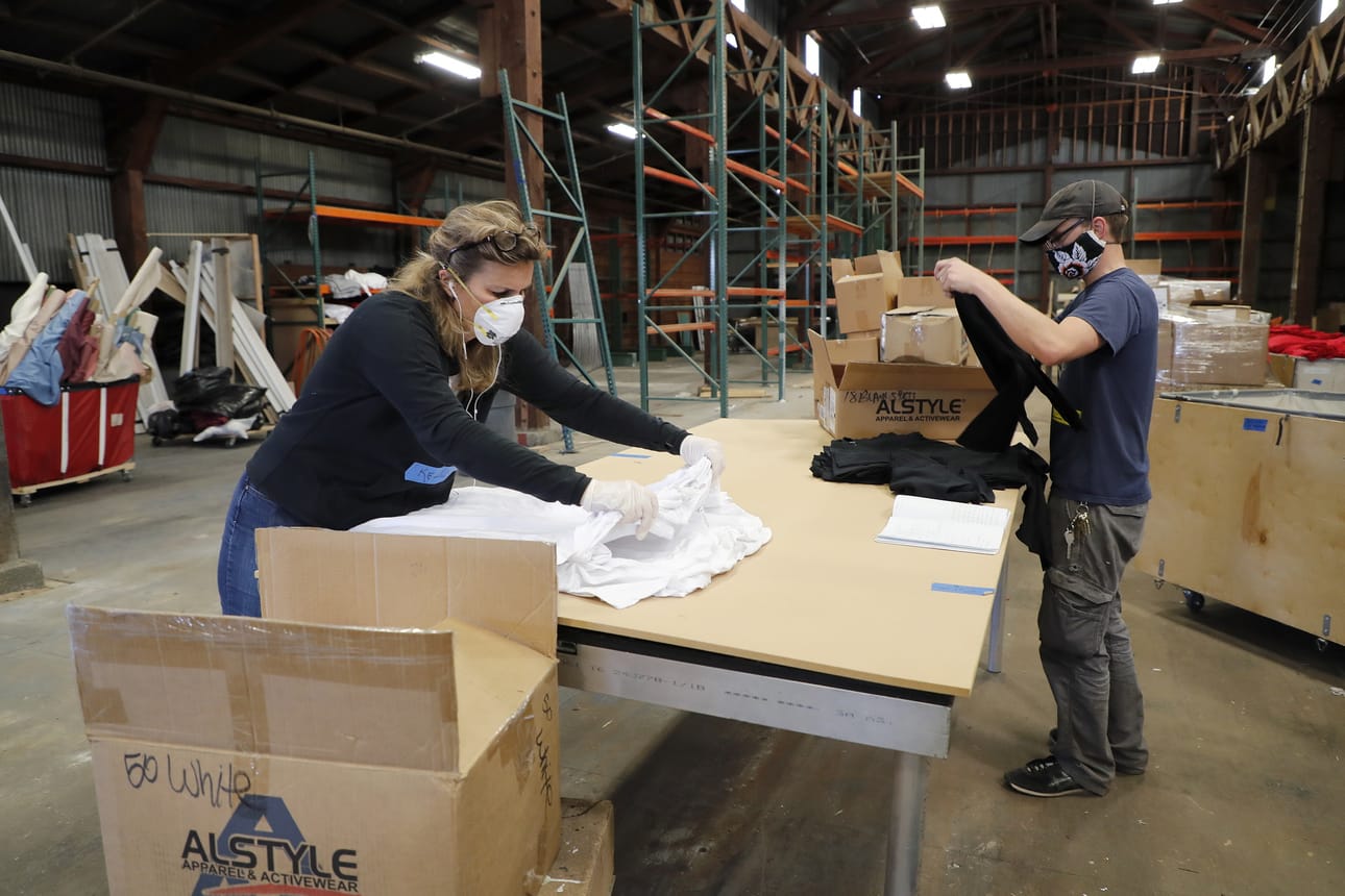 Vapaaehtoiset Kelly Barna (vas.) ja Jim Krehl ottavat paketeista materiaaleja, joista valmistetaan suojavarusteita koronavirukseen sairastuneita hoitaville Kalifornian Alamedassa perjantaina.