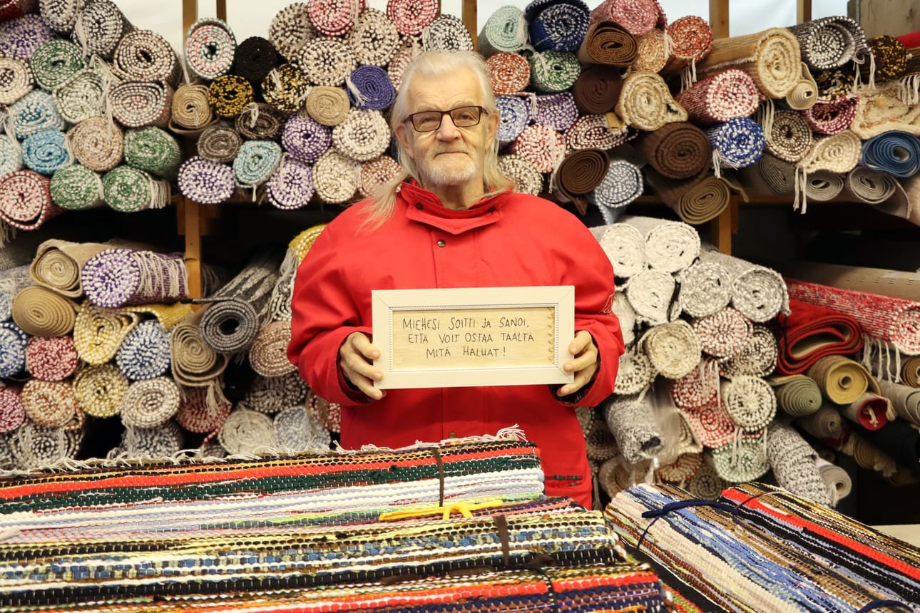 "Miehesi soitti ja sanoi, että voit ostaa täältä mitä haluat", lukee taulussa mattokauppias Jorma Rajasaaren käsissä. – Löysin tämän kirpputorilta. Kuin tehty tänne kauppaan, kauppias myhäilee.