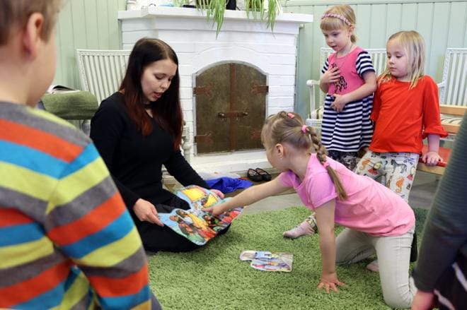 Lastenohjaaja Hanna Rajala käy läpi opetuslasten nimiä. Rajalan edessä kuvaa osoittaa Kerttu Saarepuu, taustalla Armi Hautamäki ja Erin Niemi. KUVA: JARMO PANULA