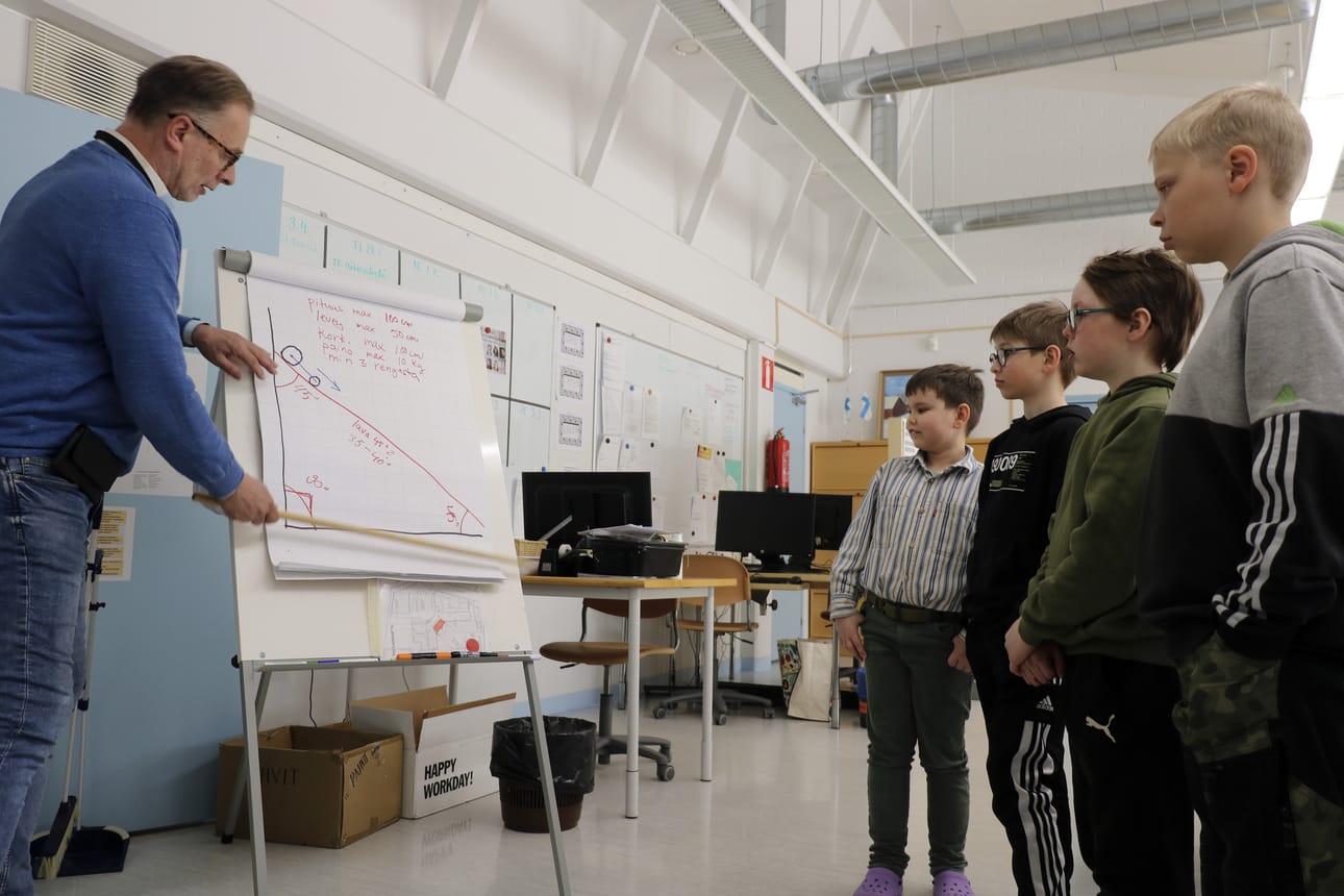 Risto Klasila opastaa oppilaille lähtölavan jyrkkyyden merkitystä liukuvan auton liikkeisiin.