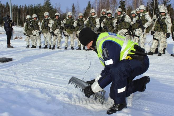 Panu Vainionpää poliisista opetti sotilaspoliiseille piikkimaton vetämistä tielle Runsorissa. Nuoret odottivat lumipuvuissaan ja rynnäkkökivääreiden kanssa. KUVA: TIINA JUUJÄRVI