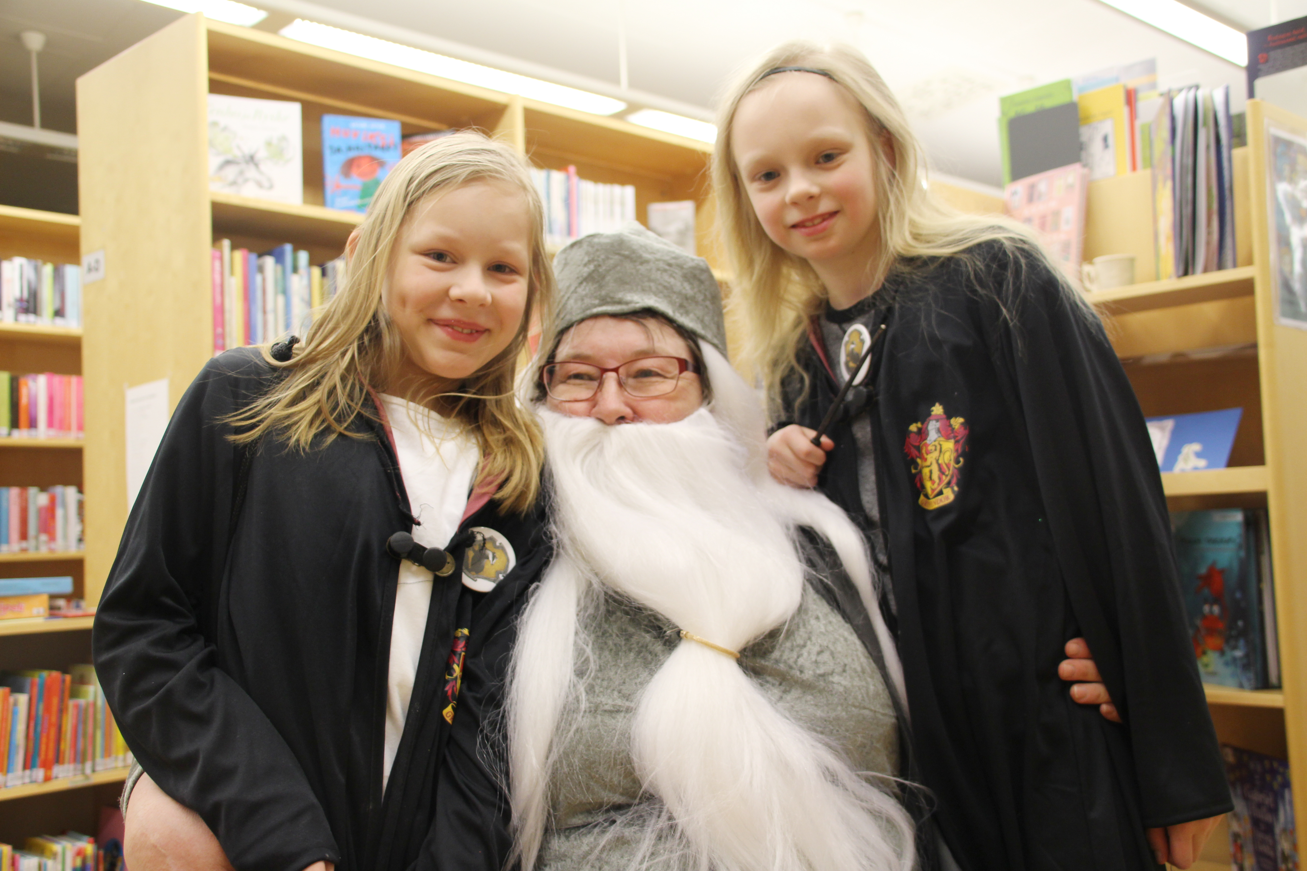 Eerika Selkäinaho ja Emilia Petäjäjärvi, Albus Dumbledoren eli kirjastovirkailija Merja Kestin halattavana.