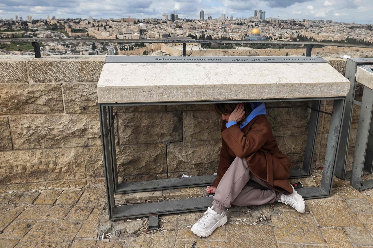 Ulkona liikkunut asukas suojautui Jerusalemissa ilmahälytyssireenien soidessa lauantaina.