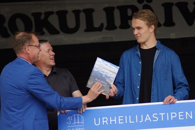 Alajärven kaupunginjohtaja Vesa Koivunen (vas.) ojentaa Otto Latvalalle 5 000 euron urheilijastipendin ja Alajärvi-kuvakirjan. KUVA: TEEMU NIEMELÄ