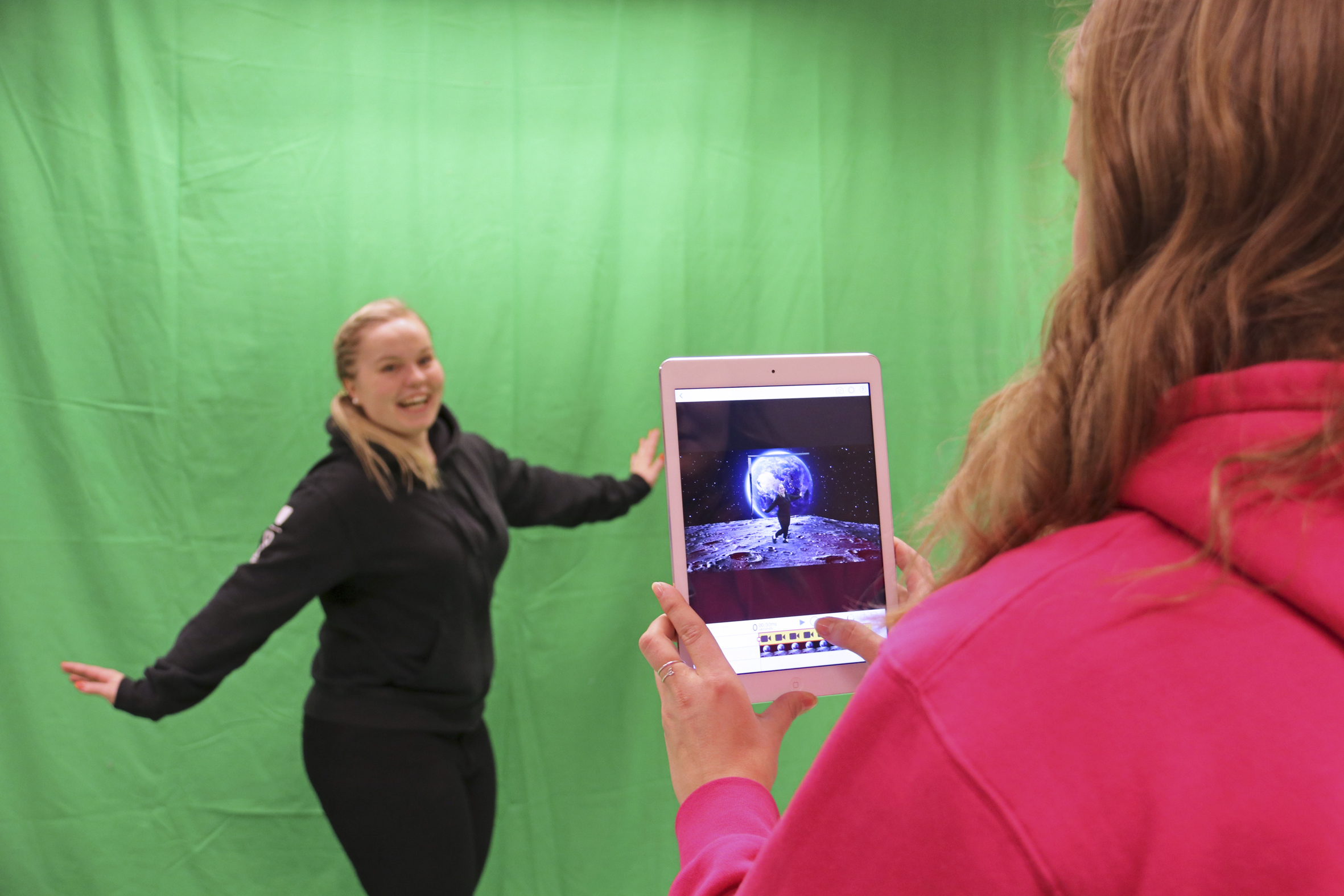 Pirita Heiskanen (kuvassa) ja Johanna Laine havainnollistivat, miten green screen toimii. Vihreän taustan ja green screen -sovelluksen avulla voi päästä vaikka avaruuteen, veden alle tai Pariisin Eiffel-tornin juurelle. ”Esimerkiksi historiaa opettaessa tämän avulla voidaan mennä ihan minne vain. Käytännössä tarvitaan vain vihreää seinää ja tabletit kouluilla usein jo on”, kouluttajat kertoivat.