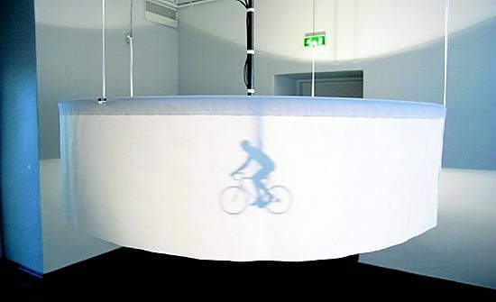 Mekaaninen pyöräilijä kiertää kankaista velodromia Matti Tainion teoksessa.